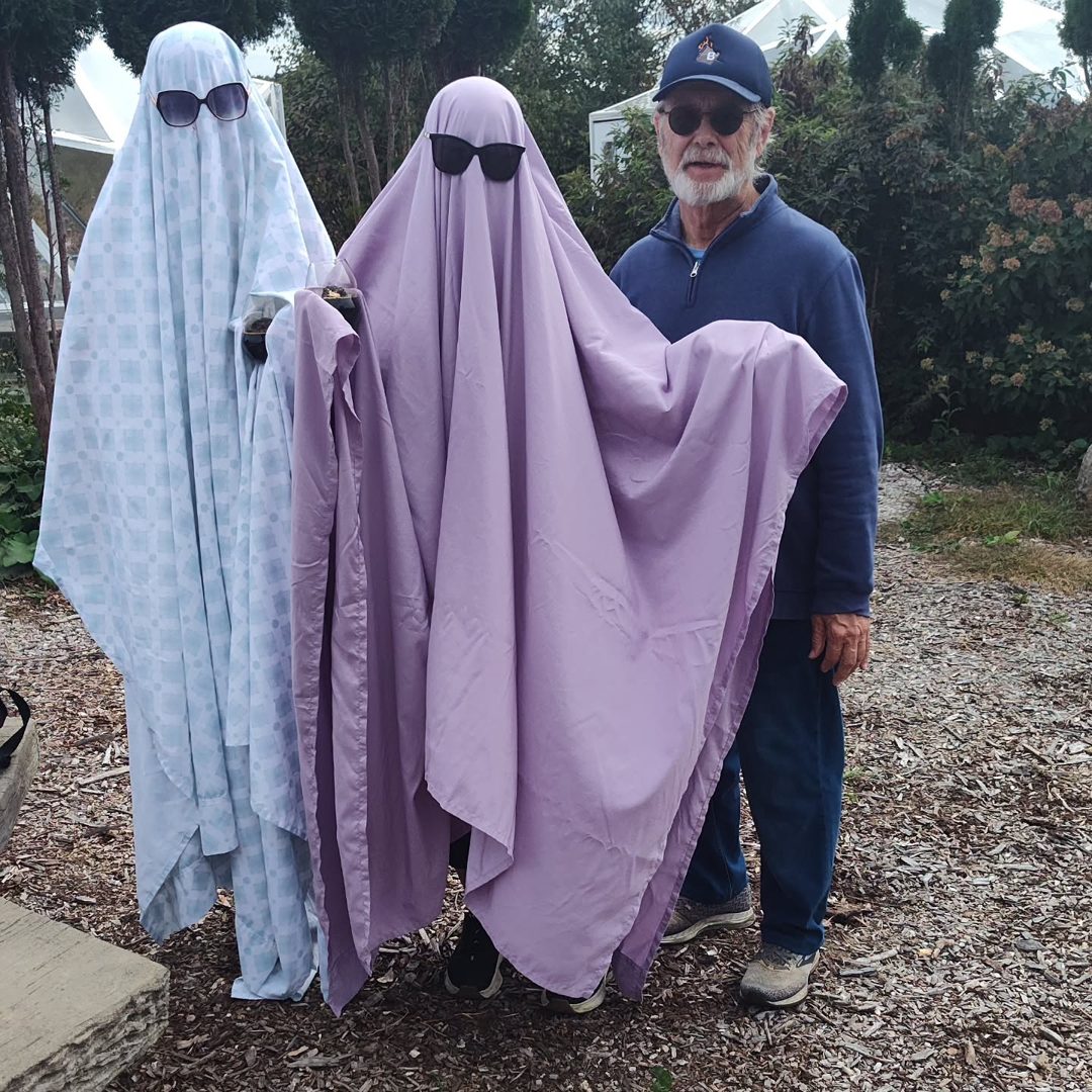 The two sunglasses-wearing sheet ghosts posing with a friend outside the winery